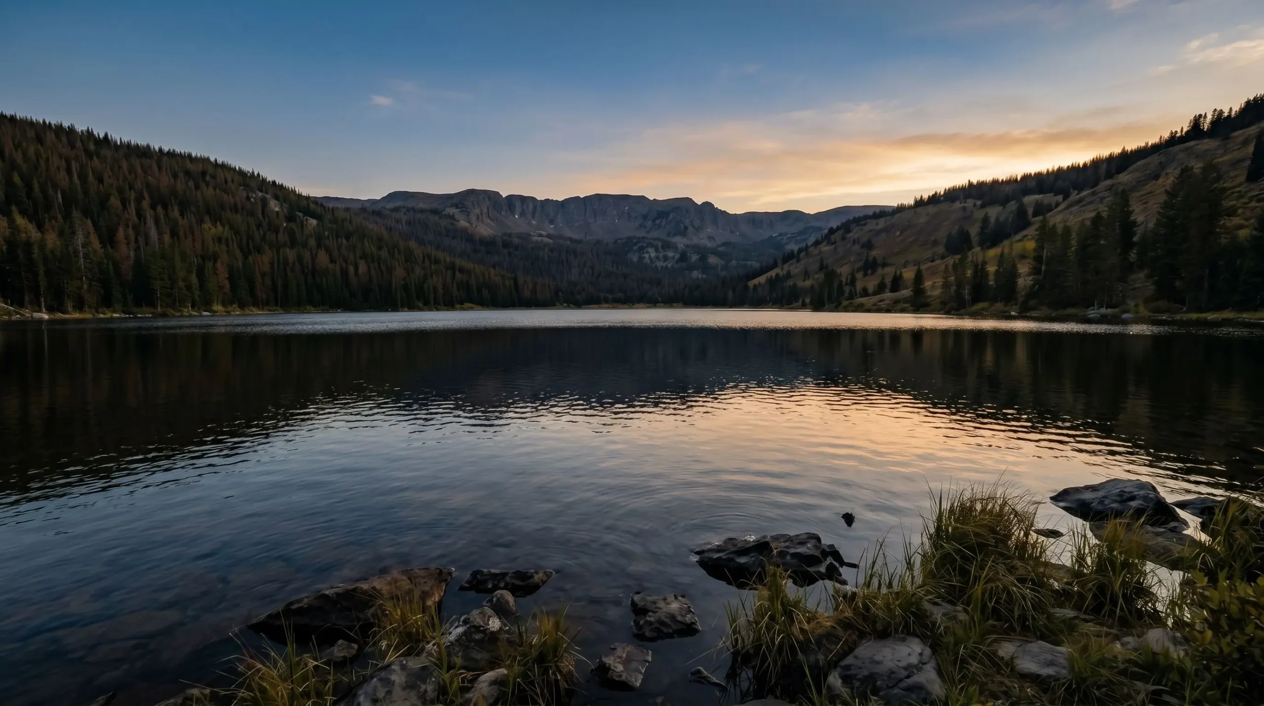 A deep mountain lake at evening, surrounded by forested hills, with subtle reflections on settled water and a warm horizon, evoking the settled wholeness Paul names as peace among the fruit of the Spirit.