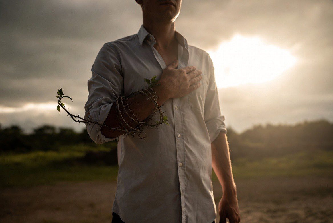 A person standing in soft morning light with a small thorned vine wrapped around the arm, symbolizing humility and God’s grace in weakness.
