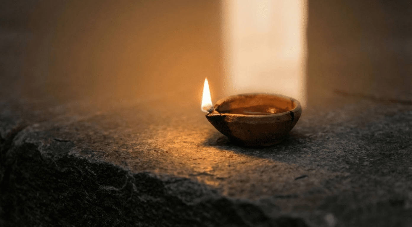 Ancient oil lamp burning with steady warm flame on stone surface near vertical band of light suggesting open doorway