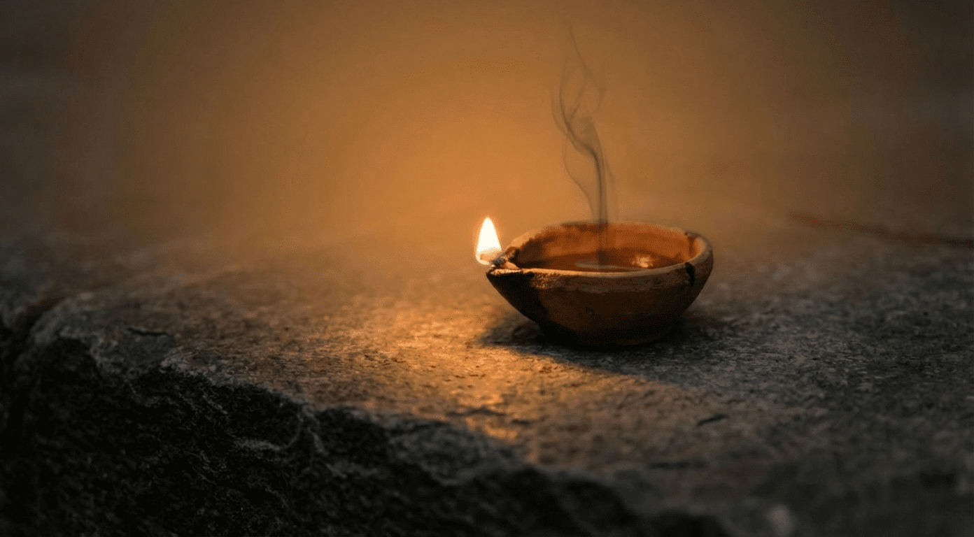Ancient oil lamp burning with warm flame and thin wisp of smoke rising on stone surface